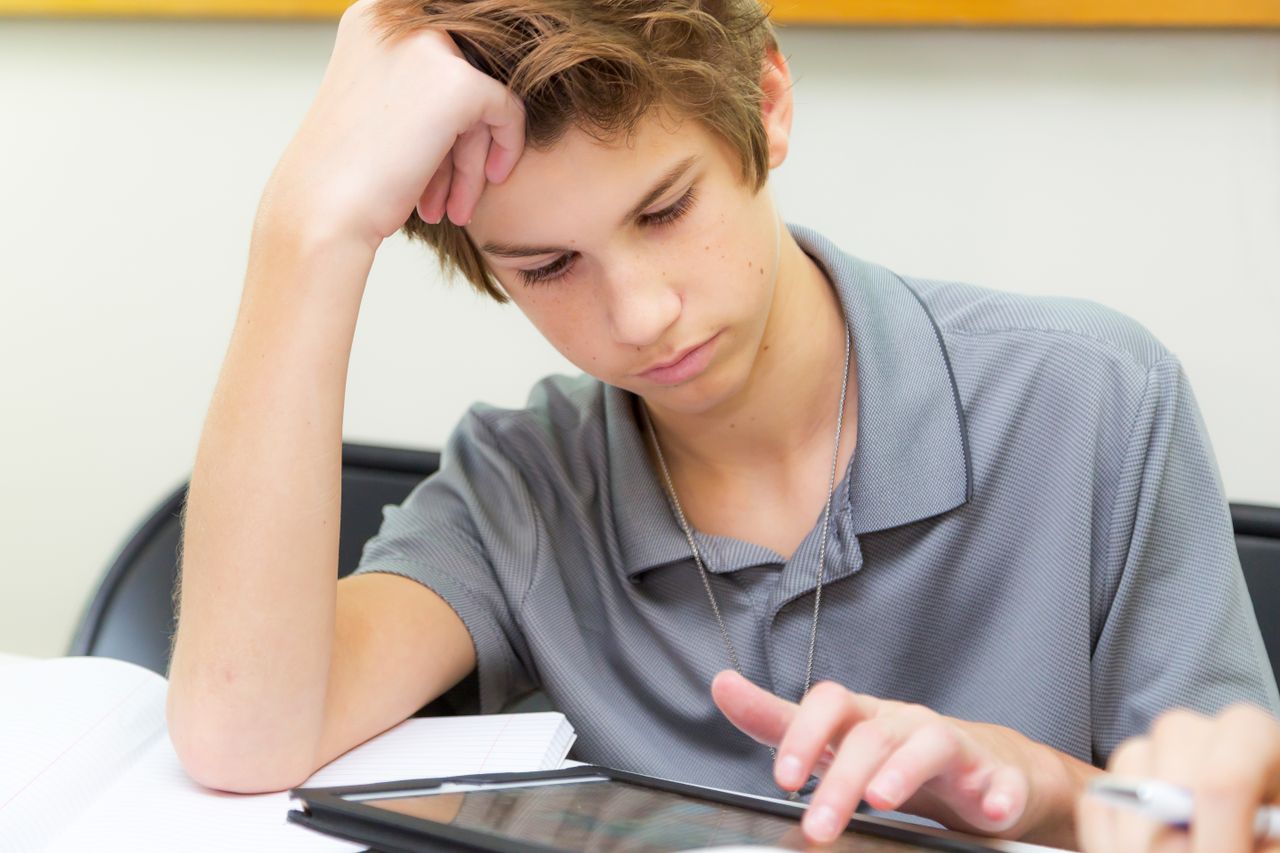 Serviços Focused teenager using a tablet for studying in a classroom environment.
