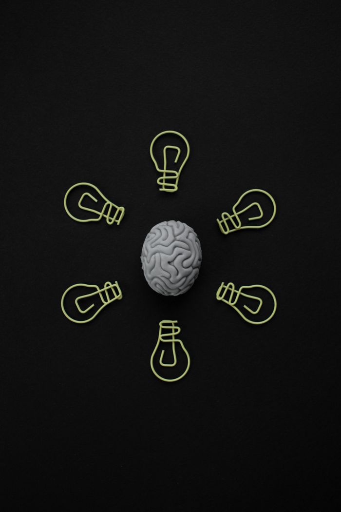Sobre Top view of a brain model surrounded by paper clip light bulbs on black background.