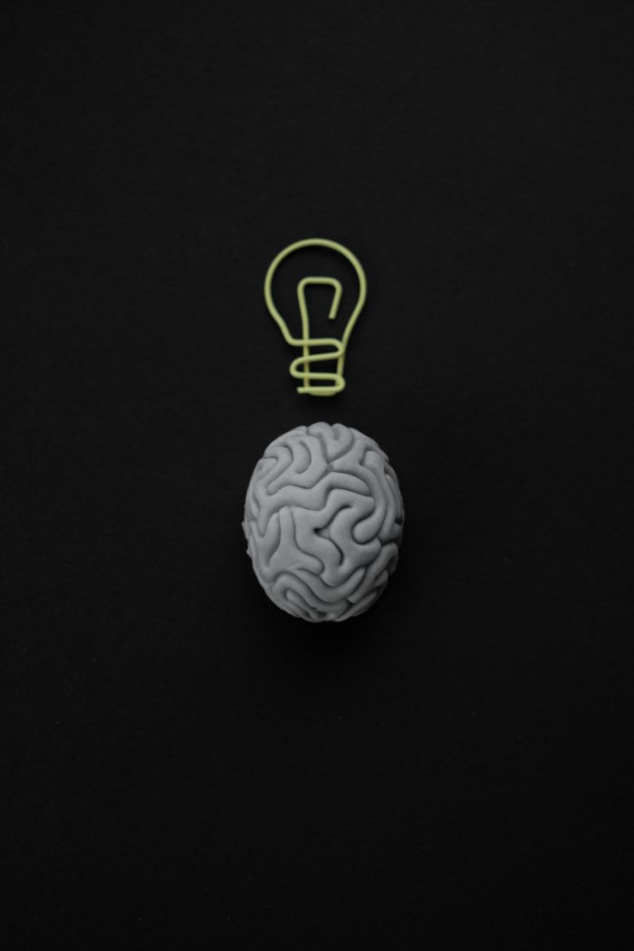 Sobre Gray brain with light bulb symbol on black background representing intelligence and creativity.