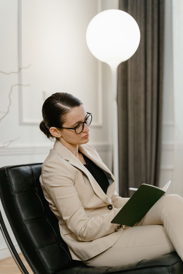 Serviços Businesswoman in glasses, seated and focused, in elegant office environment.