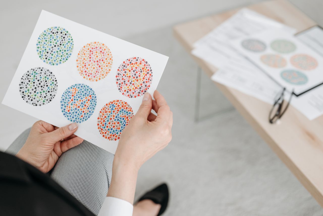 Home Close-up of a businessperson holding a color blindness test sheet with Ishihara patterns.