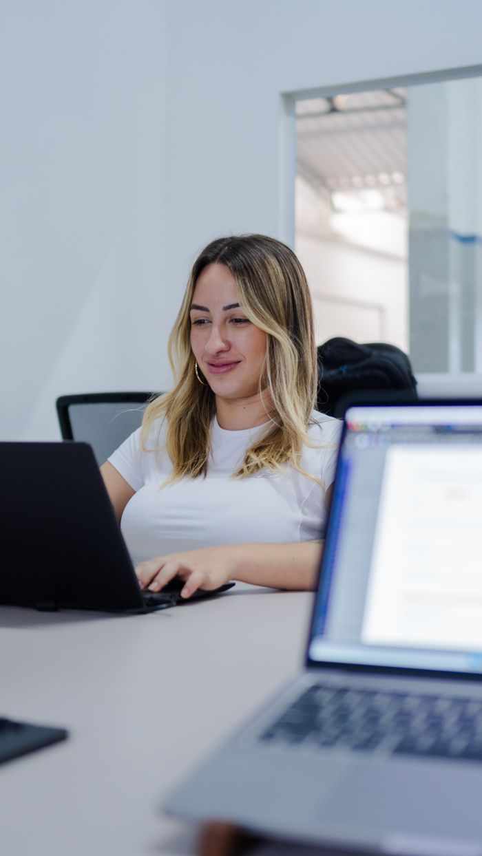 Young woman focused on her laptop screen, working in a modern office environment.