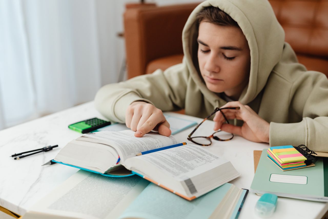Adolescente estudando em uma mesa com livros e cadernos